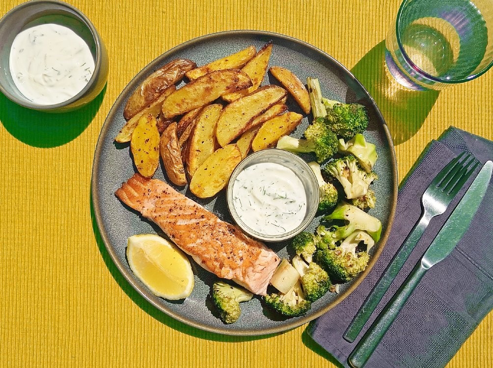 Gebratenes Lachsfilet und Kräuter-Joghurt mit Zitronenpfeffer-Kartoffelecken und Knoblauch-Brokkoli