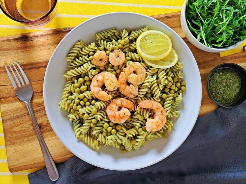 Fusilli mit Kräuterpesto und Erbsen dazu gebratene Garnelen, Rucola und Zitrone