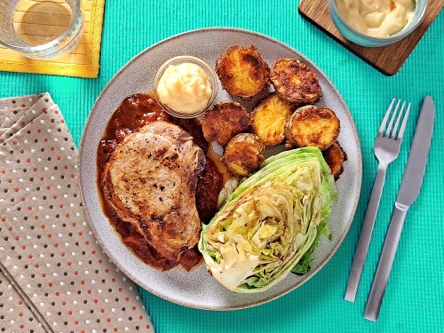 Schweinekotelett und spanische Tomatensauce mit gebackenen Käsekartoffeln, Aioli und Bratsalat 